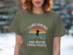 A woman in an olive green t-shirt with the text “I like hiking and maybe three people” and a silhouette of a hiker.