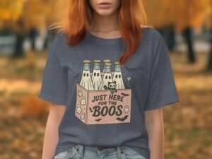 Woman with reddish hair wears a gray t-shirt featuring a cartoon graphic of bottles and the text "Just Here for the Boos."