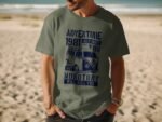 Man wearing a green t-shirt with blue text and a vintage van graphic, standing on a sandy beach.