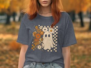 A young woman with red hair wears a gray t-shirt featuring a ghost design and flowers, set against an autumn backdrop.