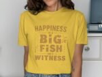 Woman in a yellow t-shirt with the phrase "Happiness is a BIG FISH and a WITNESS" printed in brown text.