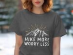 A woman in a gray t-shirt features a mountain graphic with the text "Hike More Worry Less" in white and yellow.