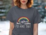 A woman in a gray t-shirt featuring a rainbow and mountains, with the text "I'd hike that" printed below.