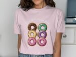 Woman wearing a light pink t-shirt featuring a graphic of six colorful donuts with the text "Check Out My Six Pack."