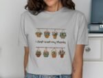 Woman wearing a light gray t-shirt with a flower pot graphic and the phrase "I Just Wet My Plants."
