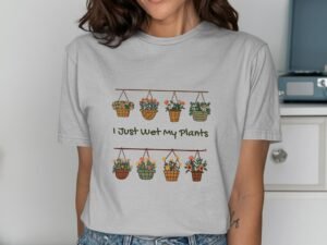 Woman wearing a light gray t-shirt with a flower pot graphic and the phrase "I Just Wet My Plants."
