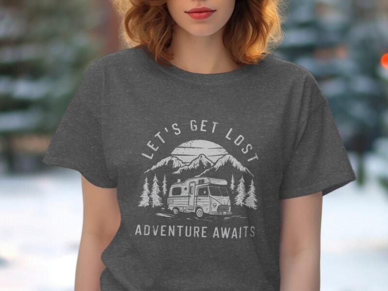 A woman wears a gray t-shirt featuring a camper and mountainous landscape with the text "Let's Get Lost Adventure Awaits."