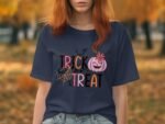 A woman with red hair wears a navy t-shirt featuring "TRICK or TREAT" text and Halloween graphics in a fall setting.