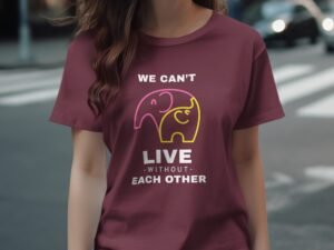 A person wearing a burgundy t-shirt featuring two cartoon elephants and the text "We can't live without each other."