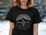 A woman with wavy hair wearing a black t-shirt featuring a mountain and heartbeat line graphic.