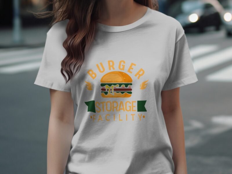A person wearing a white t-shirt with a colorful "Burger Storage Facility" graphic featuring a burger illustration.