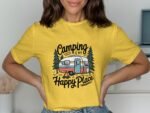 A person wearing a yellow t-shirt with "Camping is my Happy Place" and a camper illustration, smiling in a well-lit room.