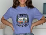 A person wearing a light blue t-shirt with "Camping is my Happy Place" graphic featuring a camper and trees.