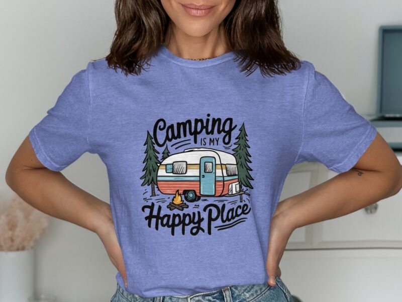 A person wearing a light blue t-shirt with "Camping is my Happy Place" graphic featuring a camper and trees.