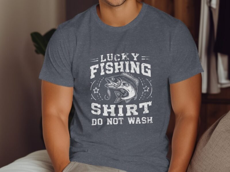 A man wearing a gray t-shirt with "Lucky Fishing Shirt Do Not Wash" and a fish graphic, seated indoors.