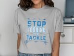 A woman wears a gray t-shirt with blue text that reads, "STOP LOOKING AT MY TACKLE," with fishing graphics.