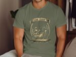 A man wearing an olive green t-shirt with a "Gone Fishin'" design featuring a fishing scene and a fisherman in a boat.