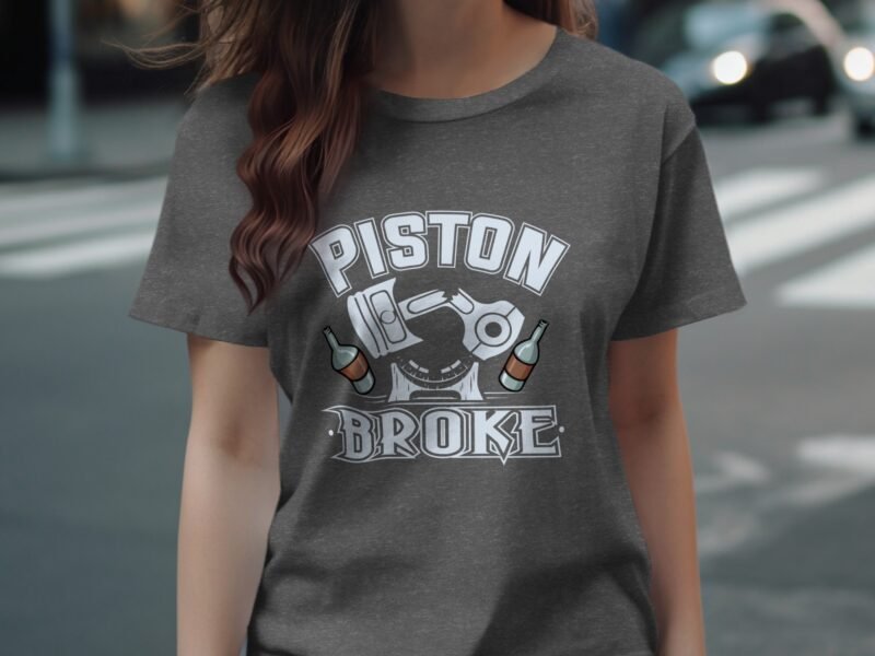 A woman wearing a gray t-shirt featuring the text "PISTON BROKE" and illustrations of a piston and bottles.