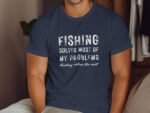 A man in a navy blue t-shirt with a fishing-related slogan printed on it, sitting in a cozy indoor setting.