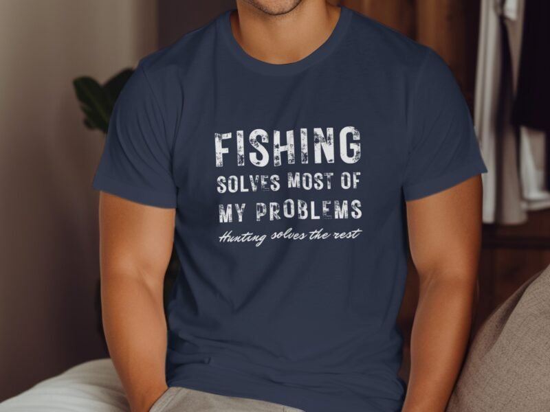 A man in a navy blue t-shirt with a fishing-related slogan printed on it, sitting in a cozy indoor setting.