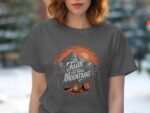 Woman wearing a gray t-shirt with a mountain graphic and the text "Faith can move Mountains." Background blurred.
