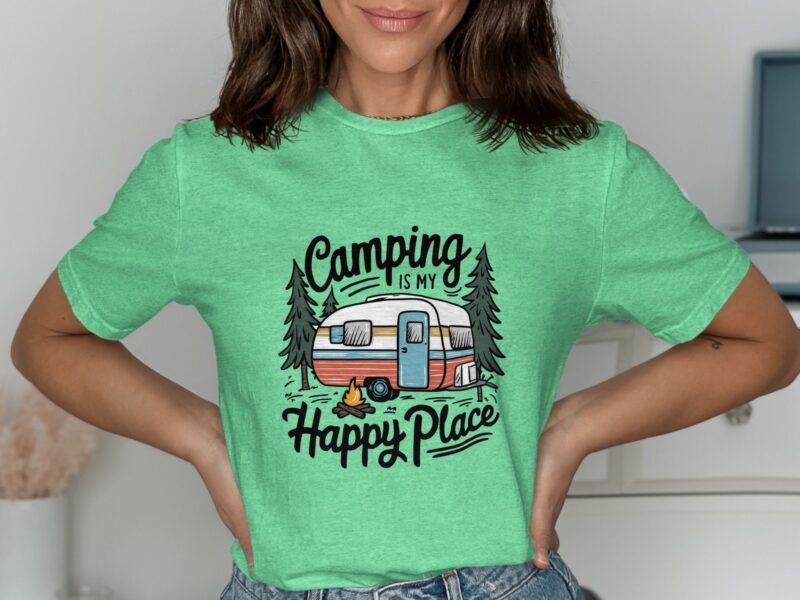 Woman wearing a green t-shirt with a camping-themed design featuring a trailer, trees, and the text "Camping is my Happy Place."