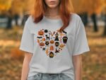 A woman with red hair wears a white t-shirt featuring a heart-shaped Halloween graphic in orange and black.