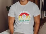A man wearing a white t-shirt with a colorful golf-themed graphic and the text about searching for golf balls.