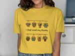 A woman wearing a yellow T-shirt with a floral design and the phrase "I Just Wet My Plants" printed on it.