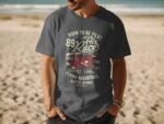 A man wearing a dark gray t-shirt with a graphic design about flying, featuring planes and text related to air racing.