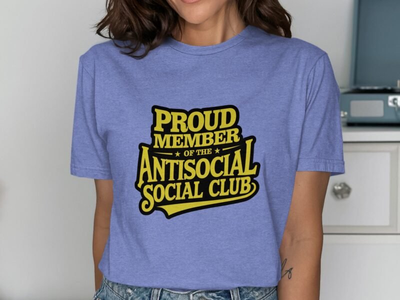 A woman wearing a light blue t-shirt with "PROUD MEMBER OF THE ANTISOCIAL SOCIAL CLUB" printed in bold yellow text.