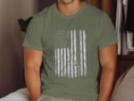 Man wearing an olive green t-shirt featuring a distressed American flag design with a spiral motif.