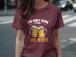 A person wearing a burgundy t-shirt with a beer graphic and the text "I'M ONLY HERE FOR THE BEER" is standing outdoors.