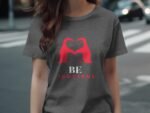 A woman wears a gray t-shirt with a red graphic of two overlapping figures and the text "BE YOUTIFUL" below.