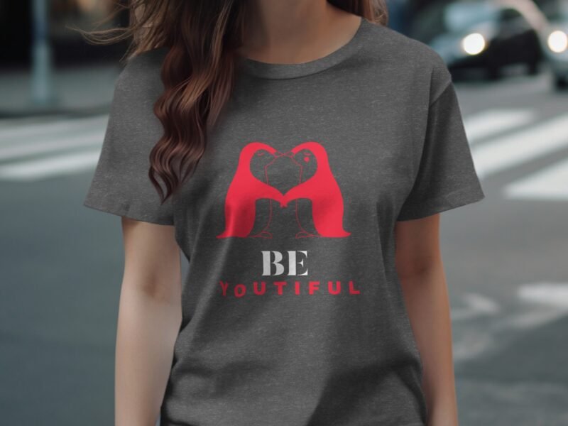 A woman wears a gray t-shirt with a red graphic of two overlapping figures and the text "BE YOUTIFUL" below.