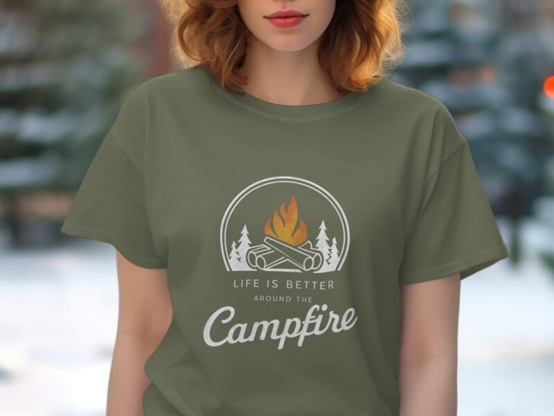 Person wearing an olive green t-shirt featuring a campfire design with the text "Life is better around the Campfire."