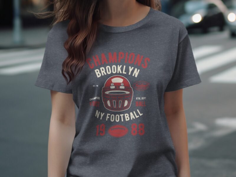 Woman wearing a gray t-shirt featuring a vintage football design with "Champions Brooklyn NY Football 1988" text.