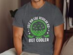 A person in a gray t-shirt with a graphic reading "GOLF KID LIKE REGULAR KID BUT COOLER," featuring a golf ball design.