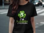 A woman wearing a black T-shirt with a recycling graphic and the text "I'M RUBBISH AT RECYCLING."