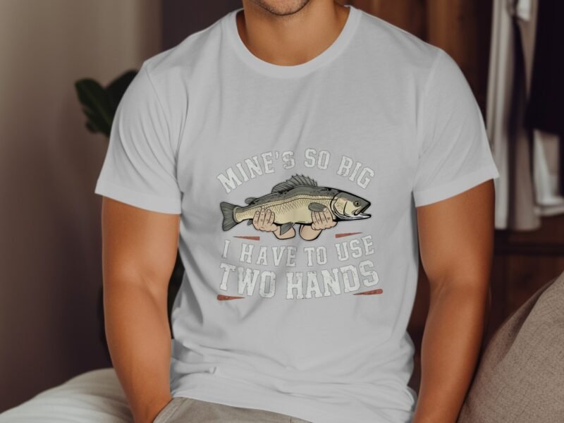 A man in a white t-shirt featuring a cartoon fish and the text "Mine's so big I have to use two hands."