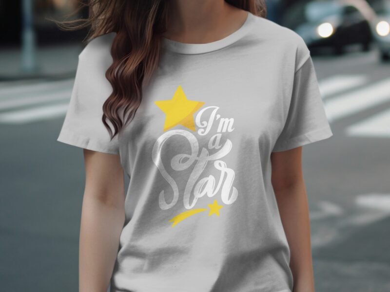 A woman wears a light gray t-shirt displaying "I'm a Star" with yellow stars on a street background.