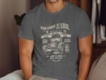 Gray t-shirt featuring vintage car graphic and retro text related to racing and speed. Model poses in a stylish setting.