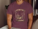 A man wearing a purple t-shirt with a fishing graphic sits casually, showcasing "Gone Fishin'" design with a boat and trees.