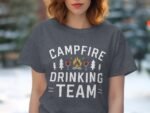 A woman wears a gray t-shirt with "Campfire Drinking Team" graphic, featuring trees, cocktails, and a campfire design.